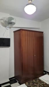um quarto com um armário de madeira e uma ventoinha em Pensión San Benito Abad em Sevilha