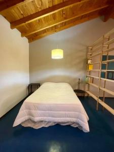 1 dormitorio con cama blanca y techo de madera en Loft Quinta Sección en Mendoza