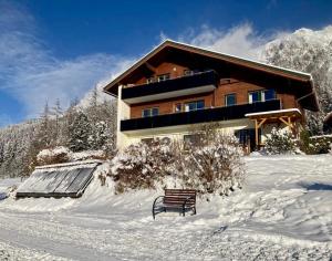 een bank in de sneeuw voor een gebouw bij Haus Werner in Ramsau am Dachstein