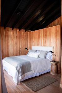 1 dormitorio con 1 cama blanca y paredes de madera en Aires Puros, en José Ignacio