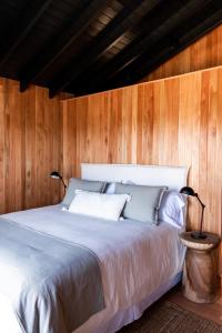 1 dormitorio con 1 cama con paredes de madera en Aires Puros, en José Ignacio