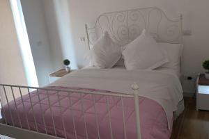 um quarto com uma cama branca com almofadas cor-de-rosa e brancas em Agasweethome Rome Gemelli em Roma
