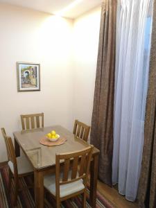 einen Esstisch und Stühle mit einer Obstschale darauf in der Unterkunft KARAULA Apartments in Sarajevo