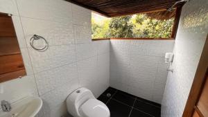 a bathroom with a toilet and a sink and a window at Tawaca ecohotel in Santa Marta