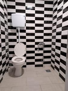 a bathroom with a toilet and black and white checkered walls at AS MONTENEGRO SUITES in Podgorica