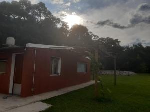 una pequeña casa roja con el sol en el fondo en Corralito Extremo en Rosario de Lerma