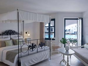 a bedroom with a canopy bed and a living room at Creta Maris Resort in Hersonissos