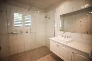 a white bathroom with a sink and a mirror at Daysy Hill Country Cottages in Port Campbell