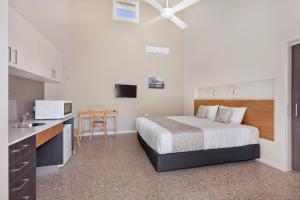 Tathra Beach House Holiday Apartments في تاثرا: غرفة نوم صغيرة بها سرير ومطبخ