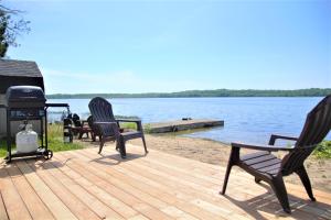 two chairs sitting on a deck next to the water at The Lake House, Couples Retreat! in Red Bay