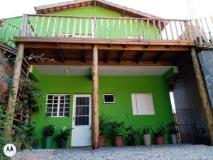 a green house with a wooden deck over the door at Chale 8A in Cunha