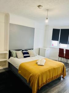 a bedroom with a bed with a yellow blanket on it at Beautiful Private Rooms in London Central Willesden Green in London