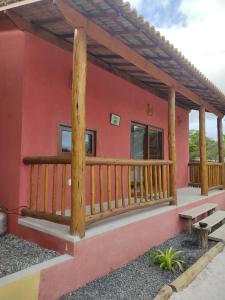Casa roja con barandilla de madera y terraza en Casas Delu Caraiva, en Caraíva