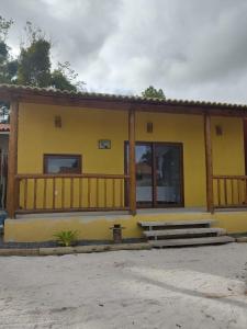 una casa amarilla con porche y escaleras delante en Casas Delu Caraiva, en Caraíva