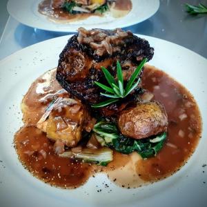 a white plate of food with meat and gravy at Last Light Lodge in Tuatapere