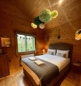 ein Schlafzimmer mit einem Bett in einer Holzhütte in der Unterkunft Hollybush Lodges in Leigh upon Mendip