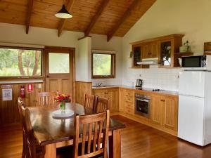 a kitchen with a table and a white refrigerator at Daysy Hill Country Cottages in Port Campbell