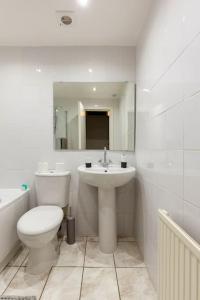 a white bathroom with a toilet and a sink at Spacious stylish centraly located flat near beach in Largs
