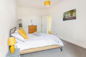 a bedroom with a bed with white sheets and yellow pillows at Spacious stylish centraly located flat near beach in Largs