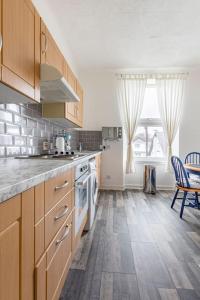a kitchen with wooden cabinets and a table in it at Spacious stylish centraly located flat near beach in Largs