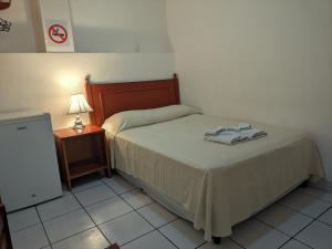 a bedroom with a bed and a lamp and a table at Hotel San Jose de la Montaña in San Salvador