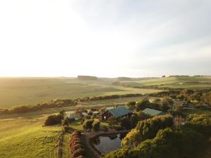 an aerial view of a farm with a house and a river at Daysy Hill Country Cottages in Port Campbell