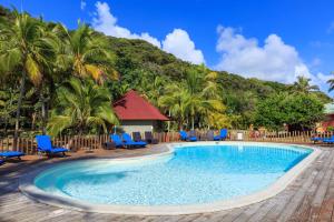 a pool at a resort with blue chairs and palm trees at Hotel Oasis de Kiamu in Lifou