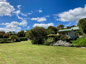 ein Haus auf einem Rasen mit Bäumen und Sträuchern in der Unterkunft Daysy Hill Country Cottages in Port Campbell
