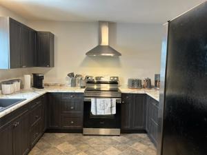 een keuken met zwarte kasten en een fornuis met oven bij Bears Den Guest House II in Churchill