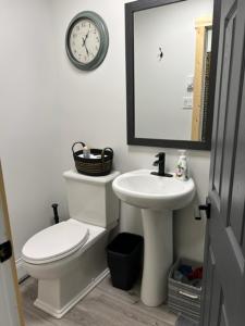 a bathroom with a toilet and a sink and a clock at Bears Den Guest House II in Churchill