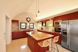 een keuken met rode kasten en een roestvrijstalen koelkast bij Villa Irene Santorini in Vourvoúlos