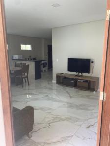 ein Wohnzimmer mit einem TV und ein Wohnzimmer mit einem Tisch in der Unterkunft Bela Casa com 3 quartos mobiliada na Zona Leste in Teresina