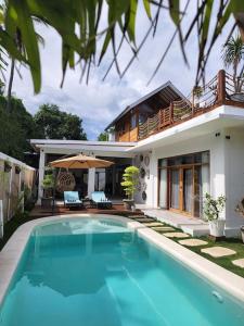 ein Haus mit einem Pool vor einem Haus in der Unterkunft Rumah Tara Modern 3 bedroom pool and garden villa in Gili Air in Gili Air