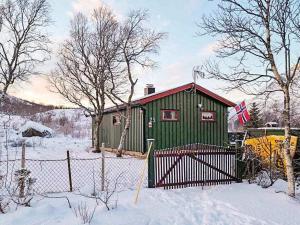 ein grünes Gebäude mit einem Zaun im Schnee in der Unterkunft Holiday home Bratland 