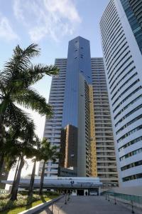 two tall buildings with palm trees in front of them at BEACH CLASS INTERNATIONAL - Flat beira mar in Recife