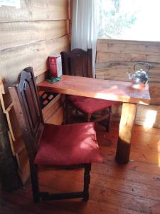 einem Holztisch mit einem roten Stuhl und einem Tisch mit in der Unterkunft Casa Ecológica Rama & Cabaña Rústica in Tandil