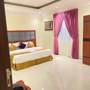 um quarto com 2 camas e cortinas cor-de-rosa em احلام الشاطئ للشقق المفروشة em Ar Ruʼays