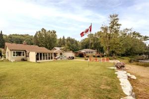 a canadian flag flying in the yard of a house at Pines Bay Waterfront cottage with Hot tub! in Kawartha Lakes
