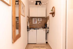 una piccola cucina con armadi bianchi e specchio di In Crowd Boho Apartment in Downtown a Zara (Zadar)