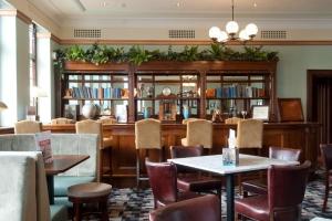 un restaurante con mesas y sillas y una biblioteca en The Greenwood Hotel - Wetherspoon en Northolt