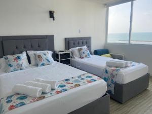 two beds in a room with the ocean in the background at FRAGATA STYLE 2 in Cartagena de Indias