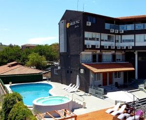 un hotel con piscina, sillas y un edificio en Capri Hotel y Cabañas by CPH en Villa Carlos Paz