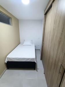Habitación pequeña con cama y puerta de madera en Condominio OASIS 207, en San Jerónimo