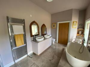baño con 2 lavabos, 2 espejos y bañera en Royal Portrush Golfing Accommodation at The Flax Mill, en Coleraine