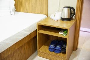 a room with a bed and a night stand with shoes at Hoo Sang Hostel 香港豪生酒店 in Hong Kong