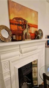 a fireplace with a painting on top of it at Private spacious studio Ealing 2 mins from tube in London