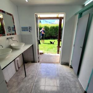 ein Badezimmer mit zwei Waschbecken und einer Person und einem Hund in der Unterkunft Lago Argentino Hostel in El Calafate