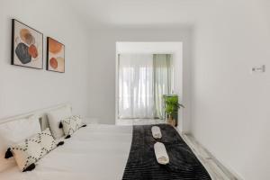 a white bedroom with a large white bed with pillows at Lovely 3-bedroom condo w/ free parking on premises in Queluz