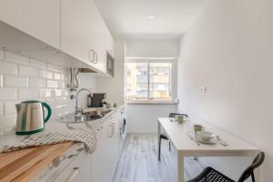 a white kitchen with a sink and a counter at Lovely 3-bedroom condo w/ free parking on premises in Queluz
