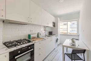 a kitchen with white cabinets and a stove top oven at Lovely 3-bedroom condo w/ free parking on premises in Queluz
